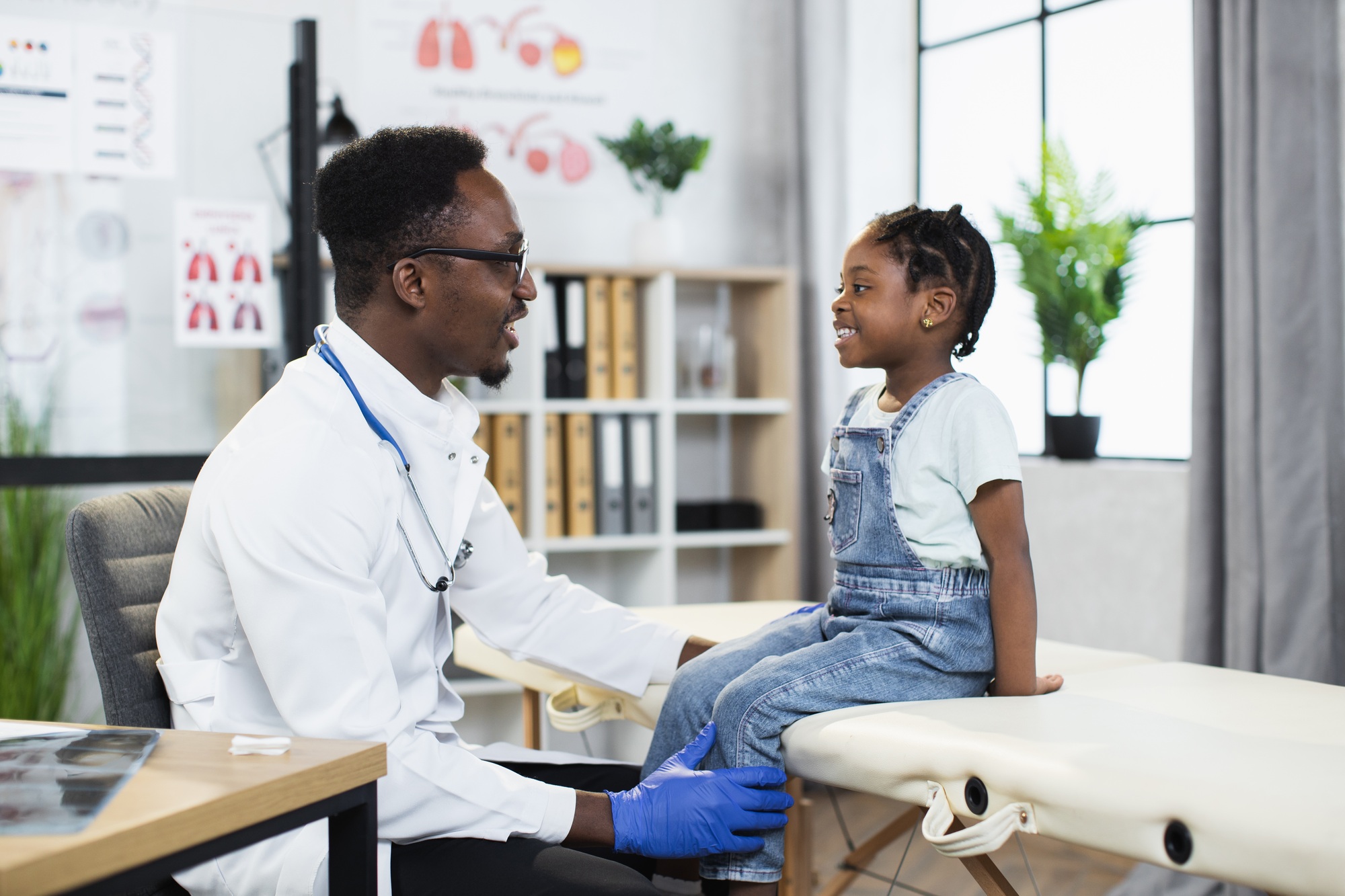 African doctor examining health of little girl at hospital